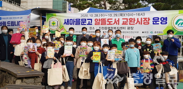 ▲ 이재철 지부장 등 새마을문고중앙회 진천군지부 회원들과 진천삼수초 어린이들이 지난 28일 진천읍 행정복지센터 앞 광장에서 진행된 ‘알뜰도서 교환시장’에서 기념촬영하고 있다.