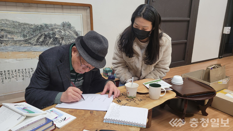 ▲ '풀꽃문학관'을 찾은 어느 팬에게 자신의 시 '풀꽃'을 붓글씨로 써주고 있는 나 시인.