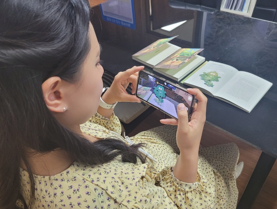 ▲ 한 주민이 휴대폰 앱으로 ‘단양의 설화를 찾아서’ AR 스토리 북을 읽고 있는 모습. 사진=단양군제공