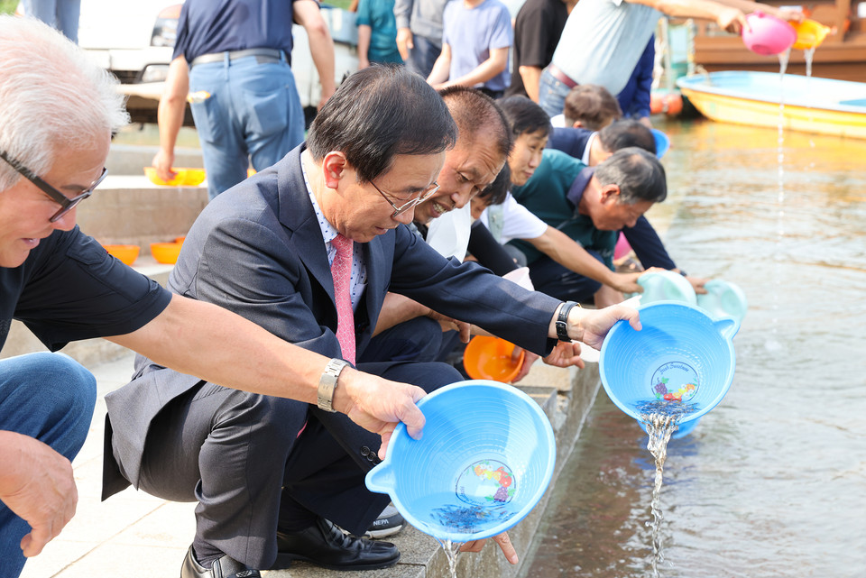 ▲ 김문근 군수(왼쪽 두번째)와 어업인들이 단양강에 쏘가리 치어를 방류하고 있다. 사진=단양군제공