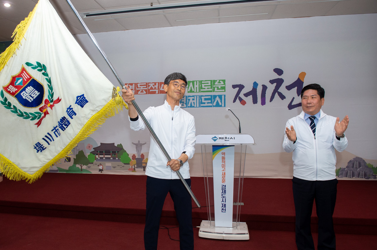 ▲ 김창규 시장(오른쪽)으로 부터 시 체육회 깃발을 전해 받은 안성국 시 체육회장이 상위권 진입을 각오하며 깃발을 힘차게 흔들고 있다. 사진=제천시제공