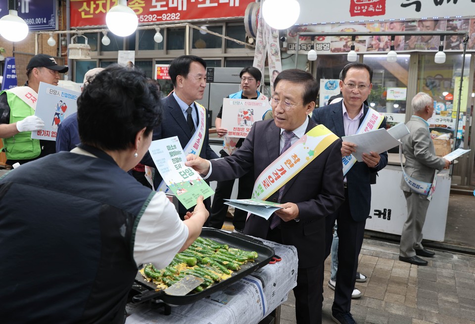 ▲ 김문근 군수(오른쪽)가 구경시장에서 상인들에게 오감만족에 동참을 촉구하는 리플릿을 나눠주고 있다. 사진=단양군제공