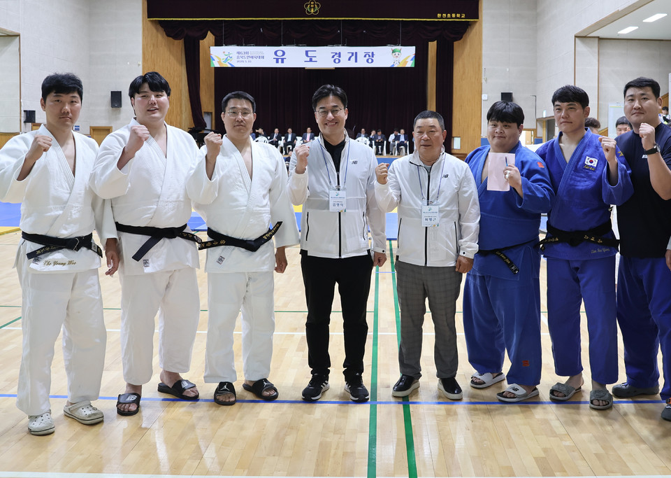 김명식 진천군 체육회장(가운데)이 유도경기장에서 선수들과 기념촬영하고 있다..