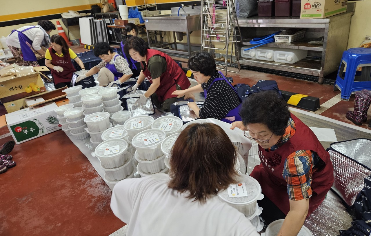 ▲ 단양군여성단체협의회가 영양 가득 만들어진 삼계탕을 배달할 용기에 담고 있다. 사진=단양군제공