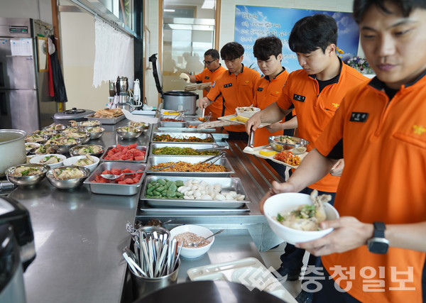 ▲ 충북 진천소방서 대원들이 25일 소방서 구내식당에서 남성의용소방대에서 제공한 삼계탕을 식판에 담고 있다.