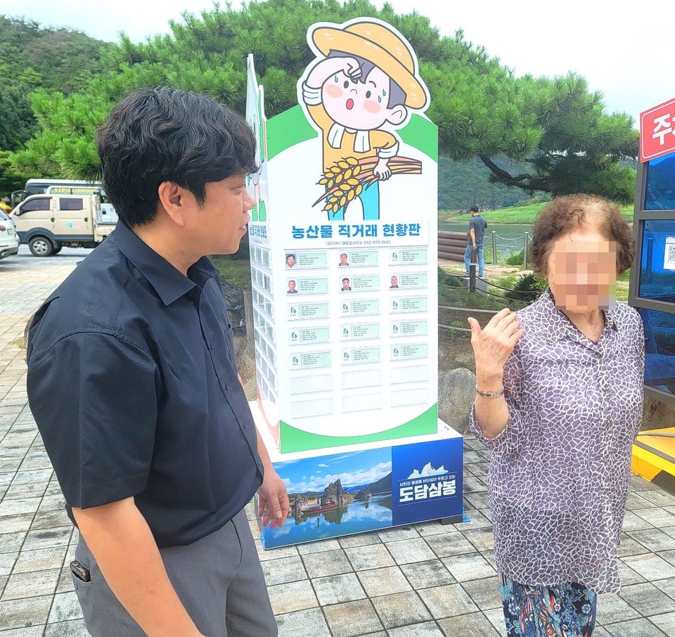 ▲ 매포읍사무소 직원(왼쪽)이 한 관광객에게 농산물을 소개하고 있다. 사진=단양군제공