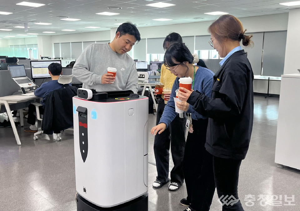 ▲ 현대엘리베이터 직원들이 14일 승강기-로봇 연동 배달 서비스를 통해 주문한 음료를 배달로봇에게서 받고 있다.