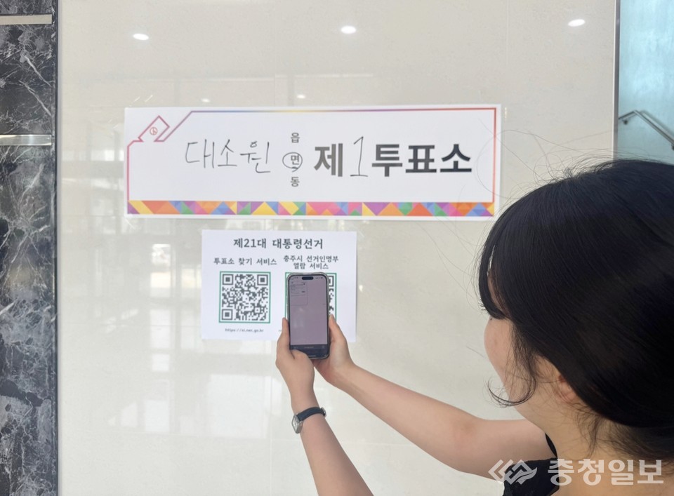 ▲ 충주시 대소원면의 한 유권자가 1투표소 벽면에 게시된 '투표소 찾기 연결서비스' QR 코드를 이용해 자신의 선거인면부 등재번호를 찾고 있다.