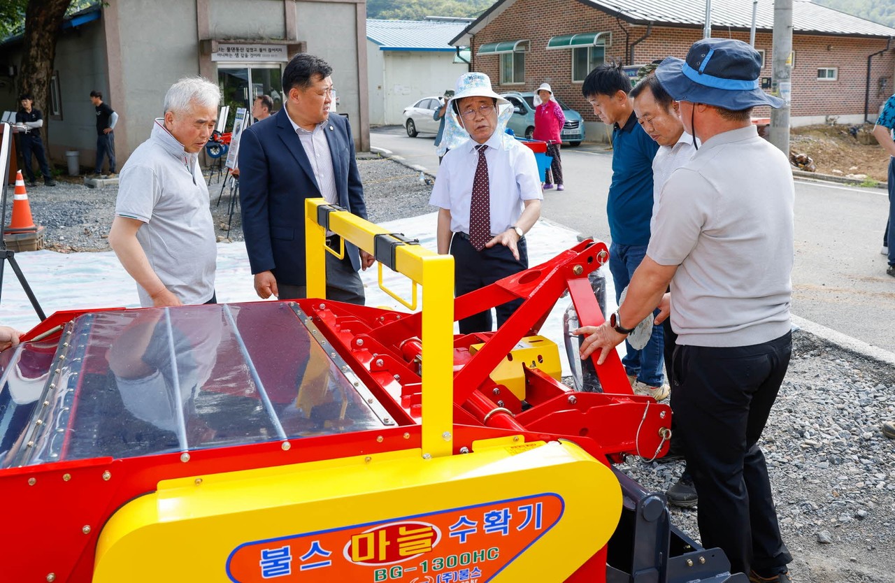 ▲ 김문근 단양군수(가운데)가 업체로부터 마늘 수확기 사용 설명을 듣고 있다. 사진=단양군제공