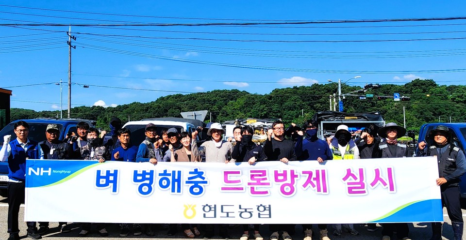 ▲ 성홍규 현도농협 조합장(앞줄 가운데)과 임직원들이 드론 공동방제에 앞서 벼 재배 조합원들과 함께 기념촬영을 하고 있다.