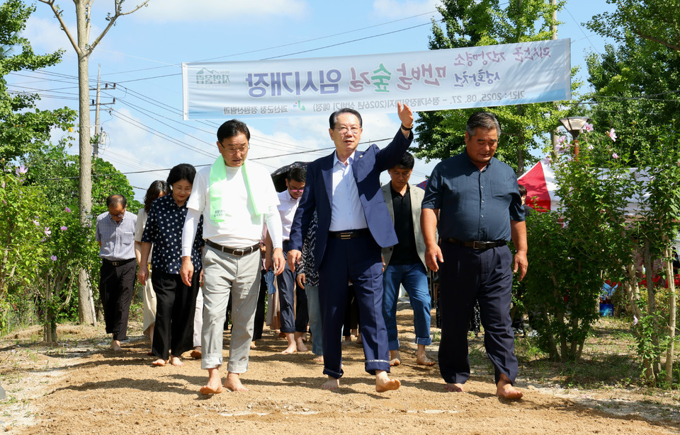 ▲ 송인헌 충북 괴산군수(가운제)와 참석자들이 성황천 맨발숲길 임시 개장식 후 맨발로 숲길을 걸으며 개장을 기념하고 있다.