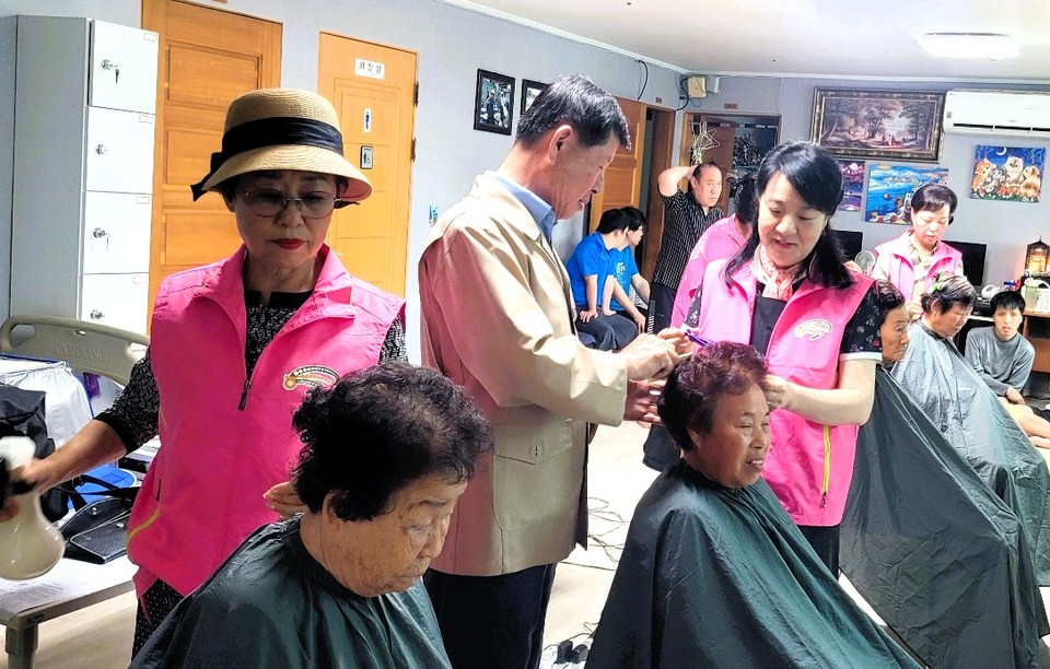 ▲ 이화준 조합장(가운데)이 청주 은혜의집에서 이·미용 봉사를 하는 봉사단을 격려하고 있다.