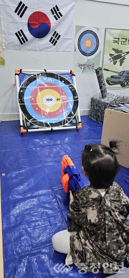 ▲ 군복 차림의 어린이가 장난감 총을 들고 과녁판을 향해 겨누며 사격 놀이를 체험하는 모습