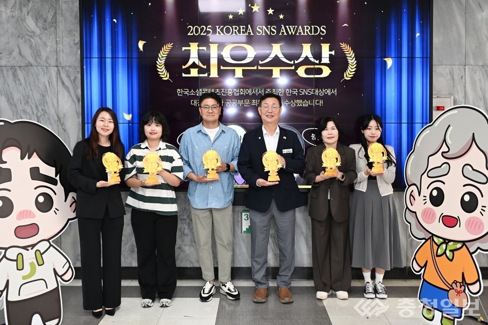▲ 김제선 대전 중구청장(오른쪽 세 번째)과 중구청 홍보팀 직원들이 ‘2025 대한민국 SNS 대상’ 시상식에서 기초지자체-자치구 부문 최우수상을 수상한 뒤 트로피를 들고 포즈를 취하고 있다. 양옆에는 중구 대표 캐릭터 ‘손자 중구’(왼쪽)와 ‘중구 할매’(오른쪽) 조형물이 함께 자리해 따뜻한 분위기를 더했다