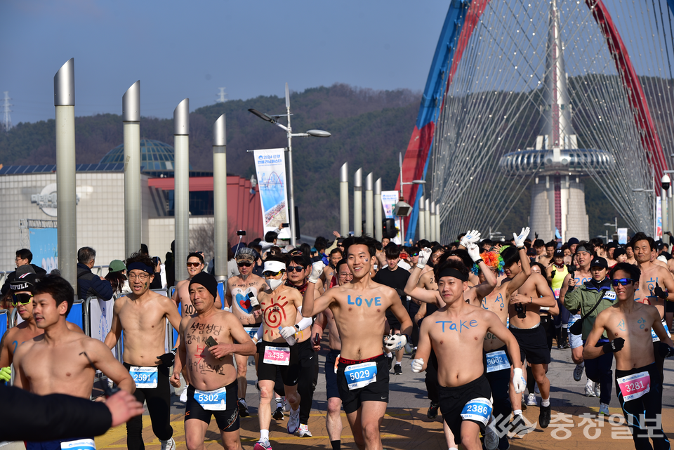 ▲ 대전 엑스포과학공원 갑천대교 위를 달리는 ‘2025 선양 맨몸마라톤’ 참가자들이 활기찬 표정으로 힘차게 레이스를 이어가고 있다. 참가자들의 몸에는 ‘LOVE’, ‘TAKE’, ‘행복’, ‘희망’ 등 새해의 긍정 메시지가 적혀 있으며, 한겨울 추위 속에서도 웃음과 열정이 가득한 축제의 장이 펼쳐지고 있다. 사진=㈜선양소주 제공