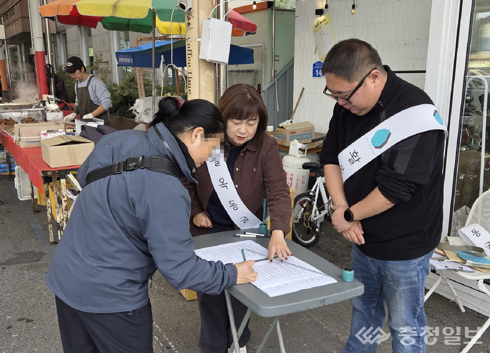▲ 충주의 한 상가 거리에서 한 시민이 '활옥동굴 양성화 촉구 및 생존권 보호를 위한 서명운동'에 참여하고 있다.