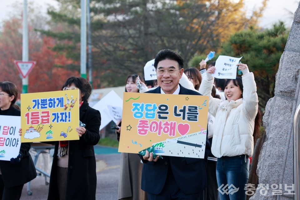 ▲ 이응우 계룡시장이 2026학년도 수능일 아침, 밝은 표정으로 응원 피켓을 들고 수험생들을 맞이하고 있다. “정답은 너를 좋아해”라는 문구가 적힌 손팻말은 현장 분위기를 더욱 따뜻하게 만들었고, 함께 자리한 시민·교직원들의 응원 구호가 고사장 앞을 환한 격려의 공간으로 채웠다