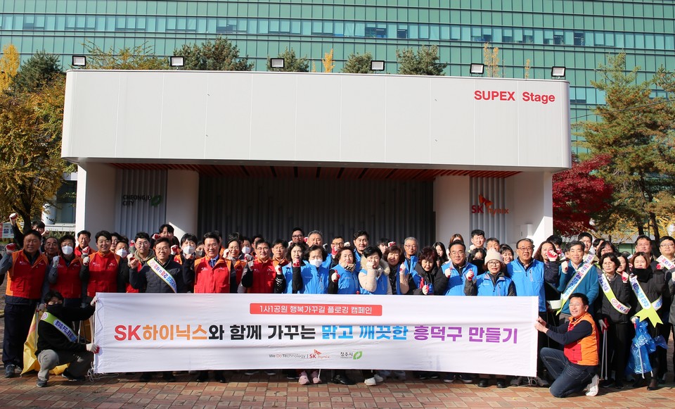 ▲ SK하이닉스 구성원들과 청주시 흥덕구청 직원 등 80여 명이 17일 솔밭공원과 인근 도로변에서 환경정화 활동을 벌이고 기념촬영을 하고 있다.
