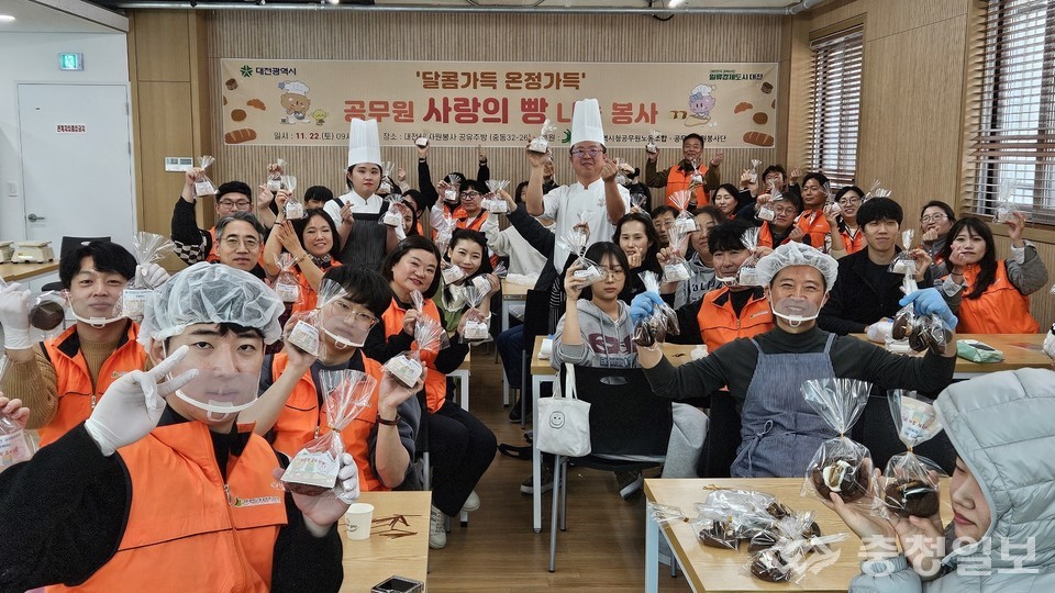 ▲ 대전시 자원봉사 공유주방에서 공무원과 가족 참여자들이 직접 만든 빵을 들고 환하게 웃으며 봉사 활동의 성과를 함께 기념하고 있다. 주방 앞에 모인 참가자들의 활기찬 모습이 나눔 활동의 따뜻한 분위기를 전한다