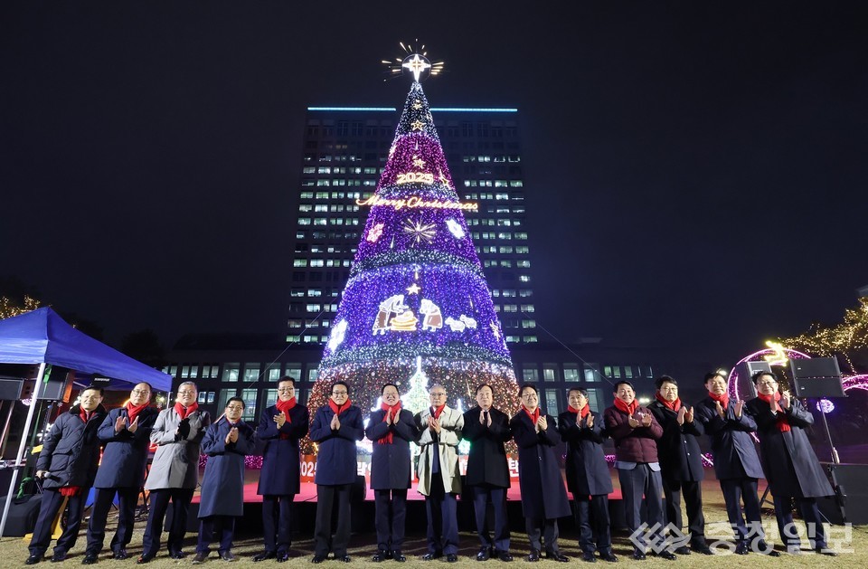 ▲ 25일 밤, 대전시청 남문광장에서 대형 성탄트리가 점등되자 관계자들이 무대 앞에 나란히 서서 축하 박수를 보내고 있다. 화려한 조명과 장식이 켜진 트리 뒤로 시청 본관이 밝게 빛나며, 겨울밤 분위기를 물들이고 있다