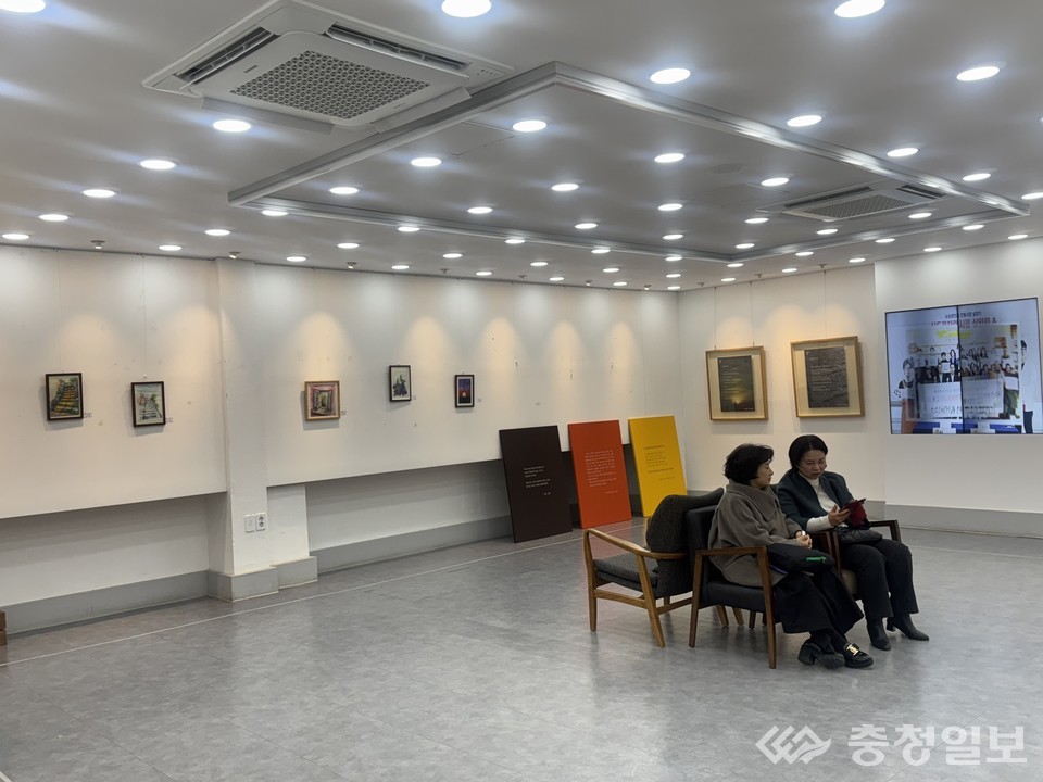 ▲ 커먼즈필드 대전 복도갤러리에서 열리고 있는 2회 허브포럼 공동전시 ‘8인의 옥타브, 풍경을 연주하다’ 전경. 복도형 공간을 따라 회화·사진·공예 작품이 이어지며, 관람객들이 일상적 동선 속에서 작품을 감상하고 있다